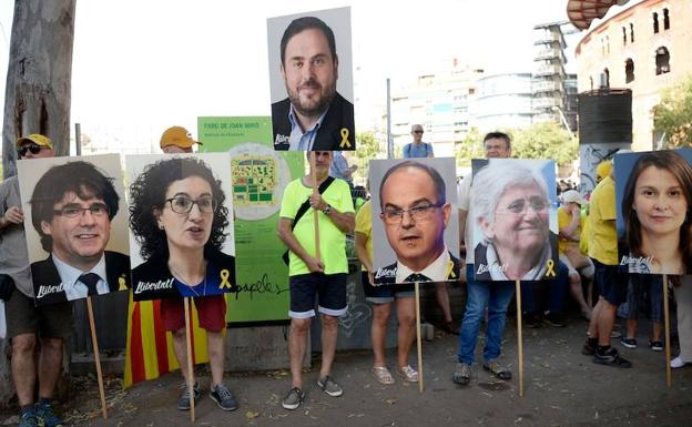 Varias personas sostienen las fotografías de los políticos implicados en el 'procés'. 