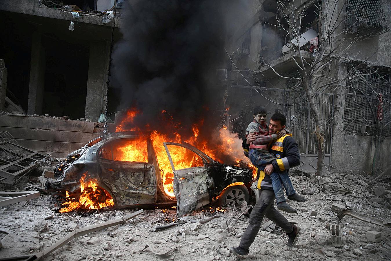 Un miembro de la Defensa Civil de Siria transporta a un niño herido en la ciudad sitiada de Hamoria, Ghouta Oriental, en Damasco, el 6 de enero de 2018.