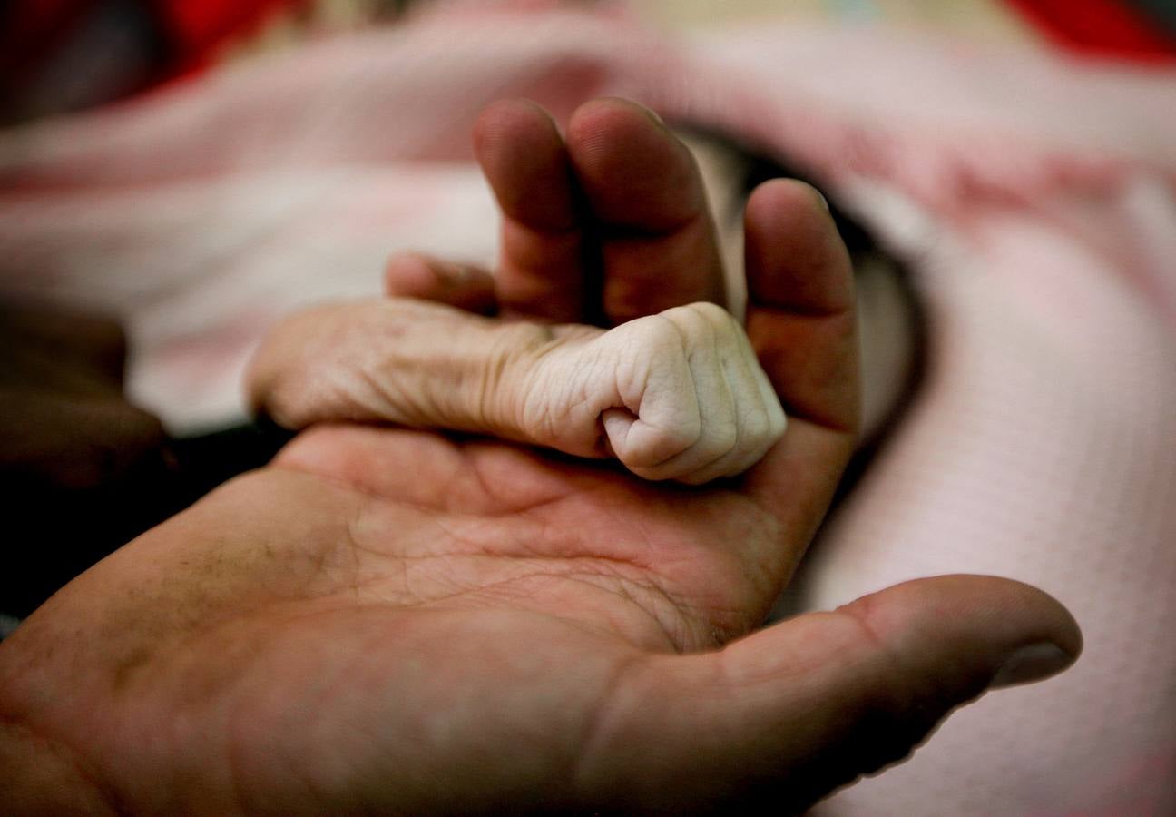 Saleh Hassan al-Faqeh toma la mano de su hija de cuatro meses, Hajar, quien murió en la sala de desnutrición del hospital Al-Sabeen en Sanaa, en Yemen.