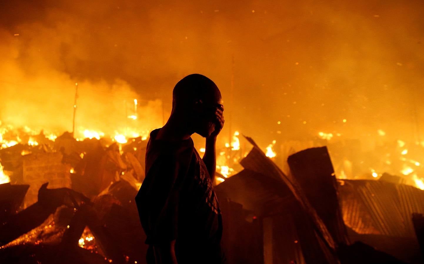 Un residente se tapa los ojos cuando intenta extinguir un incendio que se desató en Kenia.