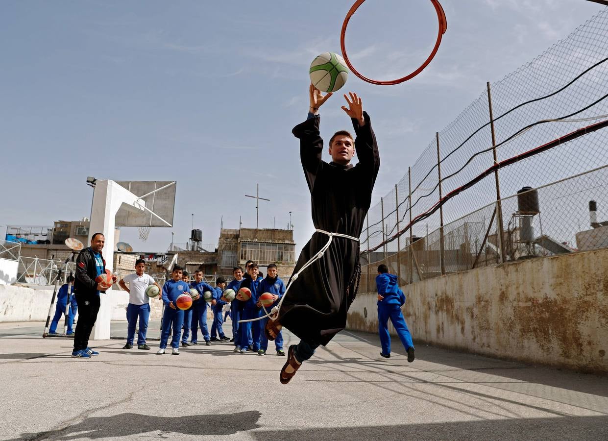 Un fraile franciscano juega al baloncesto con niños palestinos de la escuela Terra Sancta durante una sesión deportiva en la ciudad vieja de Jerusalén.