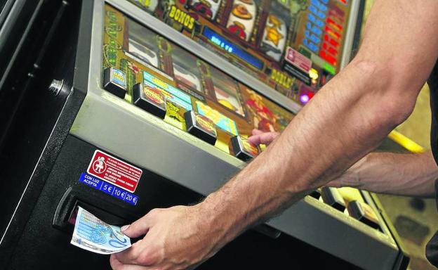 Un hombre se dispone a introducir un billete de veinte euros en una máquina 'tragaperras'.
