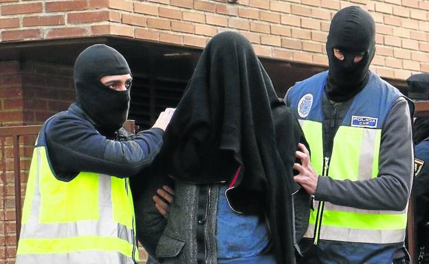 Agentes de la Policía Nacional trasladan al presunto yihadista tras el registro de su vivienda. 