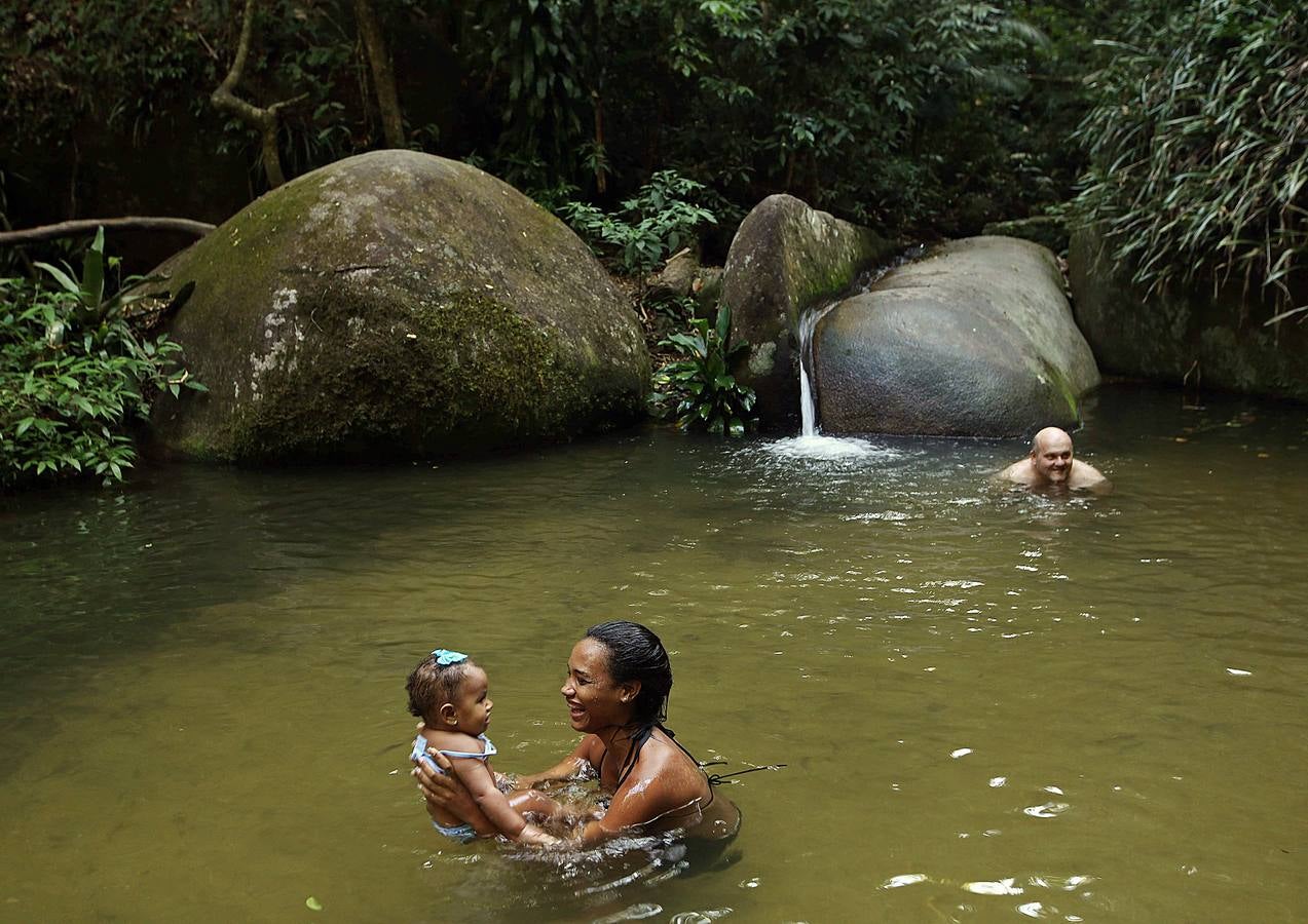 Hoy comienza el verano austral. Pero las playas de Río de Janeiro ya están llenas de bañistas desde hace unas semanas. Y es que el calor aprieta. El martes los termómetros alcanzaron 40,7 grados en la zona oeste de la ciudad, en el que ha sido el día más caluroso en varios años, con una sensación térmica de 45 grados. El mar está calmado y apenas hay olas en las transparentes aguas. Las imágenes han sido tomadas en la Floresta de Tijuca, el bosque urbano más grande del mundo, y en los arenales del oeste de Río.