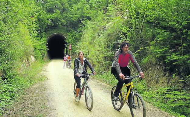 Dos ciclistas salen de uno de los túneles de la vía verde. 