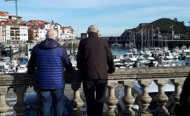Dos personas mayores de Leketio contemplan el puerto de la villa. 