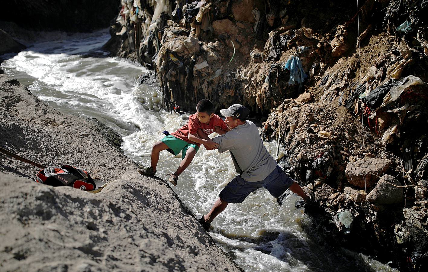 'La Mina', en la ciudad de Guatemala, se encuentra al fondo de un barranco atravesado por un río. Centenares de personas se afanan cada día entre sus aguas contaminadas, bajo la amenaza de deslizamientos y enfermedades, para tratar de encontrar objetos o chatarra con la que ganarse la vida. Algunos utilizan imanes para atraparlos, otros lo hacen a mano, introduciendo su cuerpo directamente en el agua, convertida en basurero. Si hay suerte pueden conseguir unos 20 dólares, el doble del salario mínimo. En ocasiones hasta es posible hallar un anillo o un pendiente de oro.