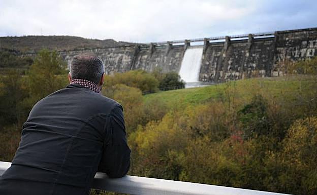Un hombre observa el desembalse del pantano, con una compuerta abierta.