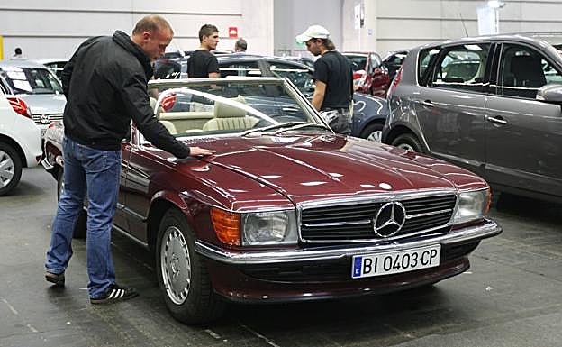 Un hombre mira un coche de ocasión. 