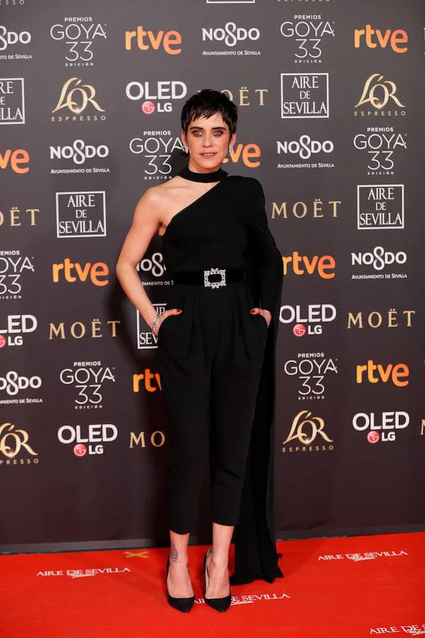 Maria León: Ha apostado por un arriesgado y diferente look con este mono asimétrico con manga larga y capa incluida de Juanjo Oliva. Ha completado el look con unos stiletto deJimmy Choo. El maquillaje en tonos tierra resalta el color de sus ojos y aporta luz a un 'total black' look mucho más renovado y juvenil.