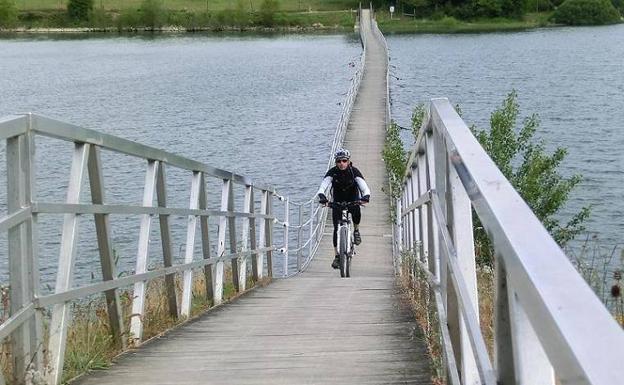 Un ciclista atraviesa una pasarela sobre el pantano. 