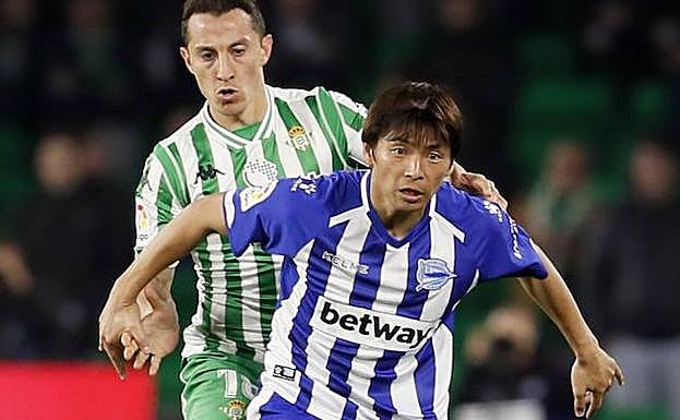 El centrocampista mexicano del Betis, Andrés Guardado, lucha un balón ante el centrocampista japonés del Deportivo Alavés, Takashi Inui, durante el partido disputado en el estadio Benito Villamarín de Sevilla. 