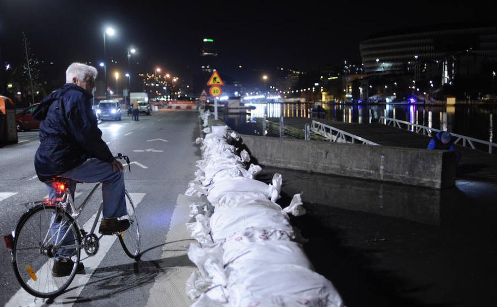 Un ciclista observa la ría a punto de desbordarse esta madrugada a su paso por Zorrozaurre. 