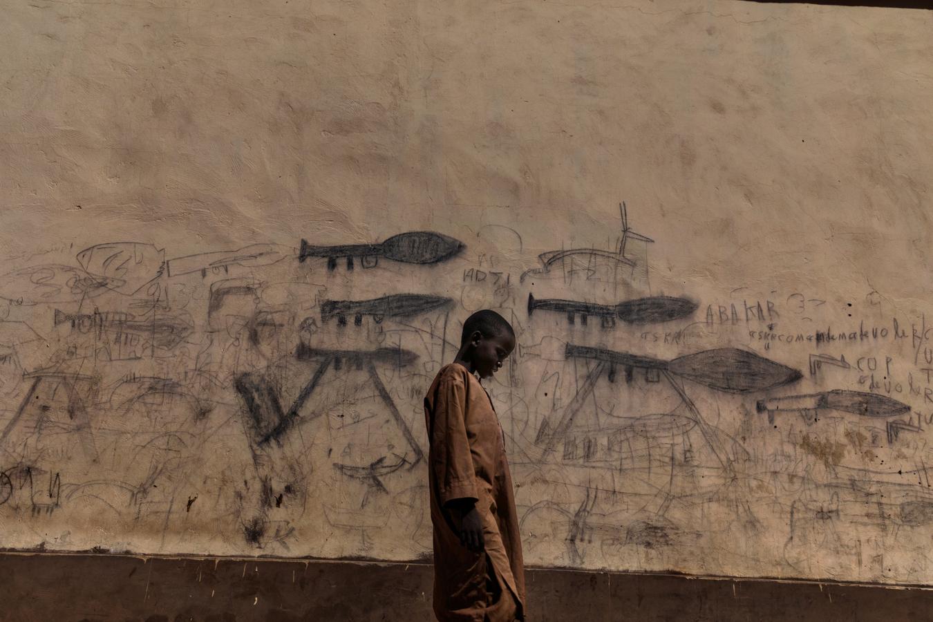 Finalista World Press Photo del año.- Un niño huérfano pasa junto a una pared con dibujos que muestran granadas propulsadas por cohetes en el país africano Chad, donde sufren una crisis que combina factores políticos y ambientales.