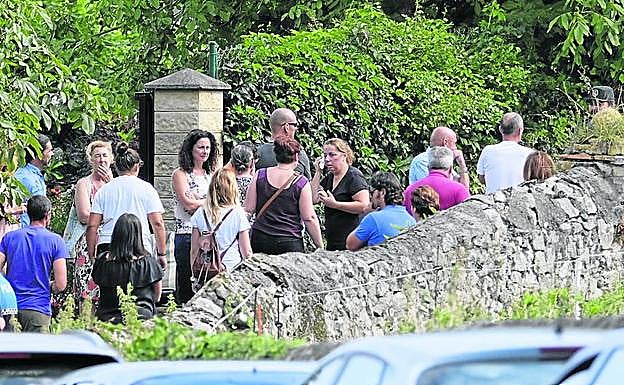 Imagen principal - Parientes y amigos de Javier Ardines el pasado 16 de agosto, tras conocerse que el concejal había fallecido junto a la casa familiar. Abajo, los perros empleados en la investigación policial y un momento del registro. 