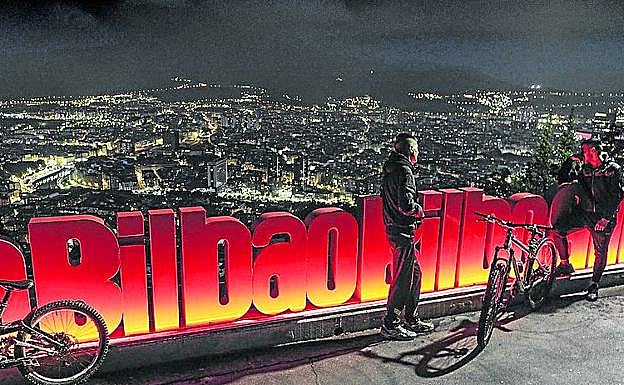 Mirador de Artxanda. Desde 2018, las palabras 'Bilbao-Bilbo' se enlazan a lo largo de una barandilla que ocupa 150 metros de largo y cuenta con una tira de luces LED. Tras las letras, en rojo, se asoma la panorámica de la ciudad.