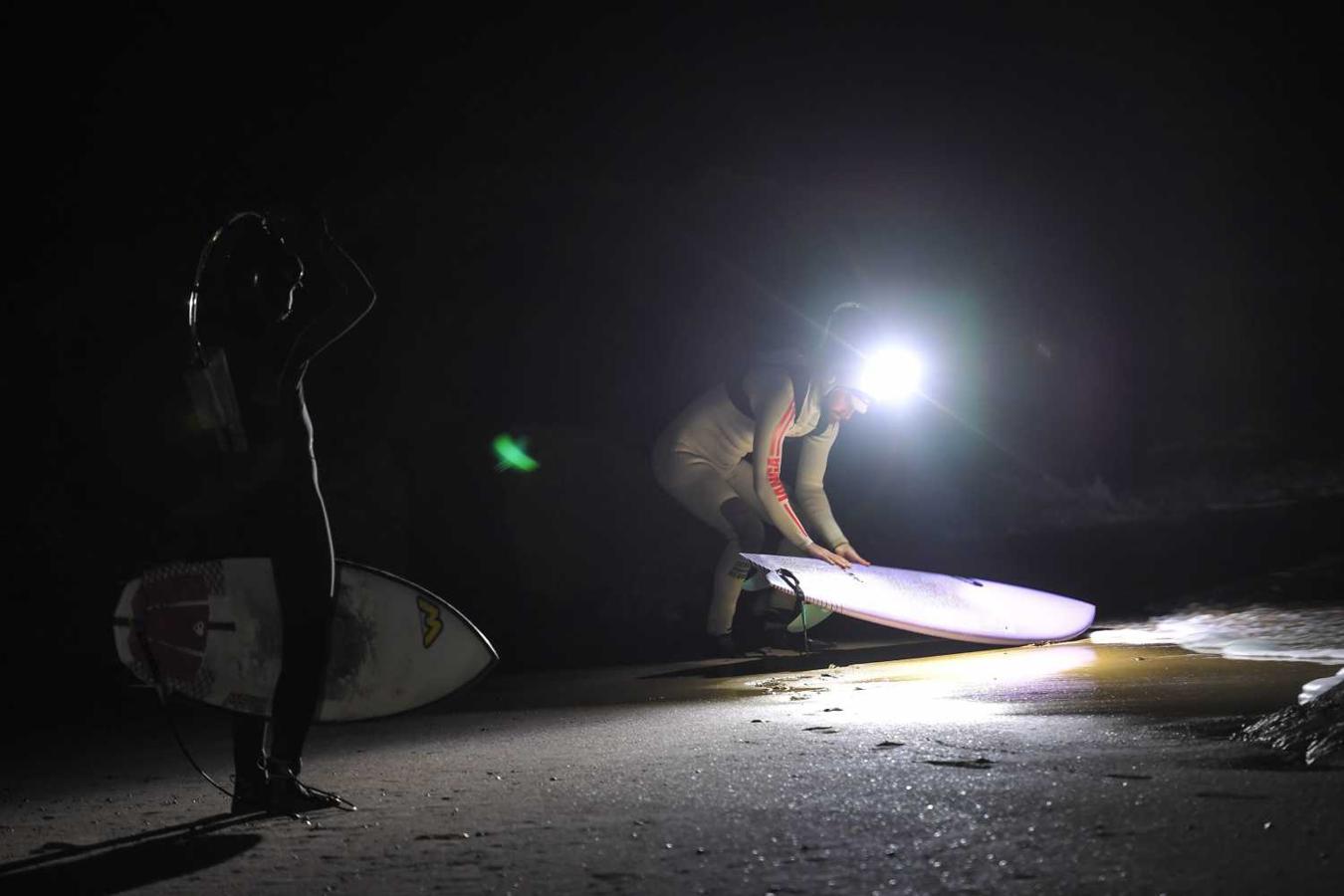 Los surfistas Yann Le Her, Alan, Yohann, Robin y Damien desafían el frío y la oscuridad en una sesión de surf nocturno en la playa del Cabo Fréhel, Bretaña