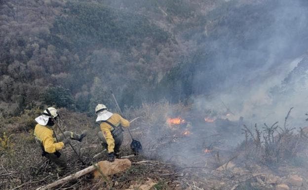 Dos guardas forestales trabajan en las labores de extinción del incendio de Muskiz.