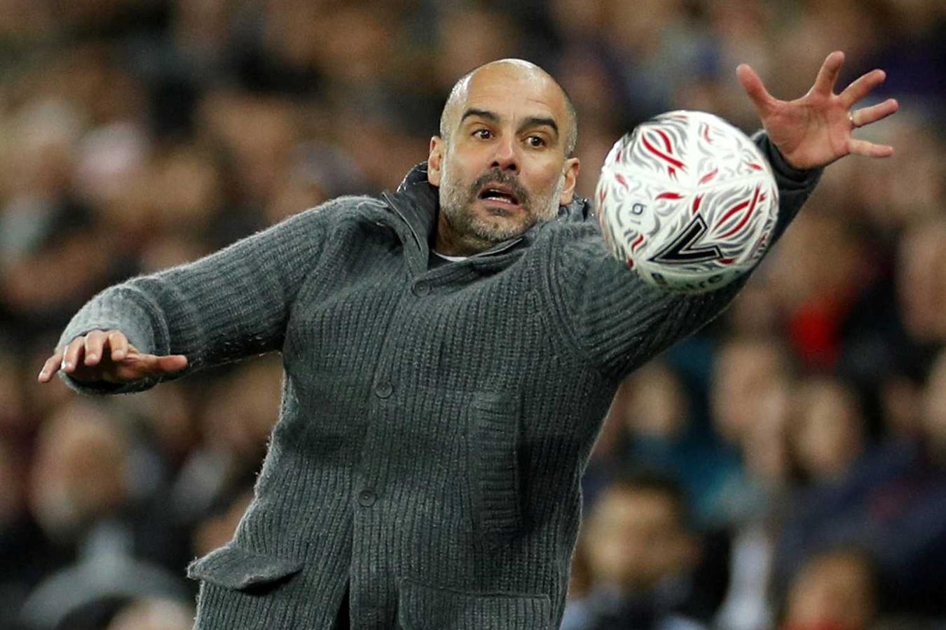 Pep Guardiola, entrenador del Manchester City, se estira para intentar alcanzar el balón durante el partido ante el Swansea City