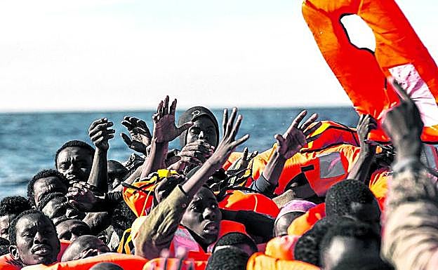 Inmigrantes subsaharianos levantan los brazos en petición de auxilio frente a las costas libias. 