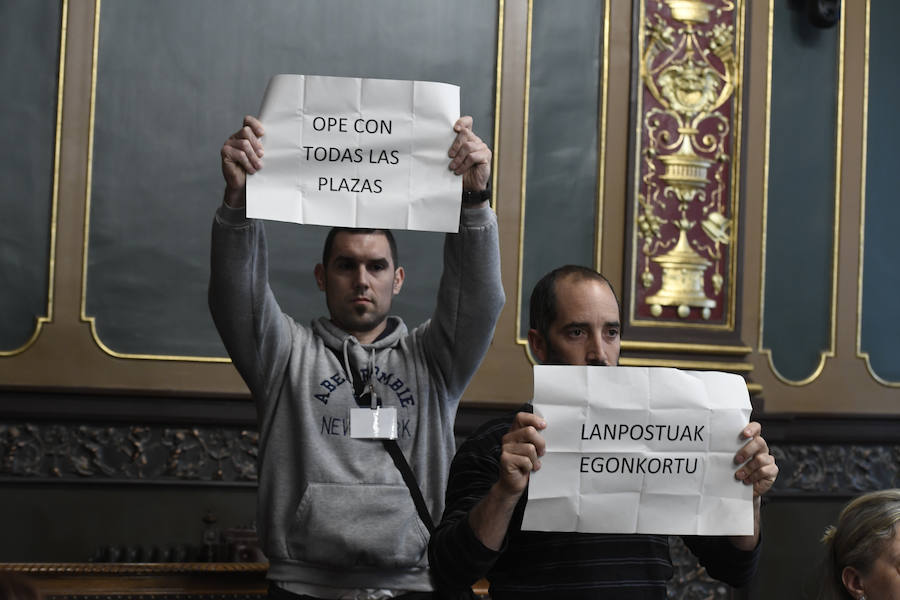 Dos jóvenes muestran pancartas durante el pleno.