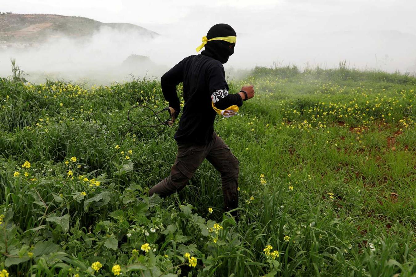 Manifestante palestino huye del gas lacrimógeno lanzado por las tropas israelíes en Al-Mughayyir, Cisjordania 