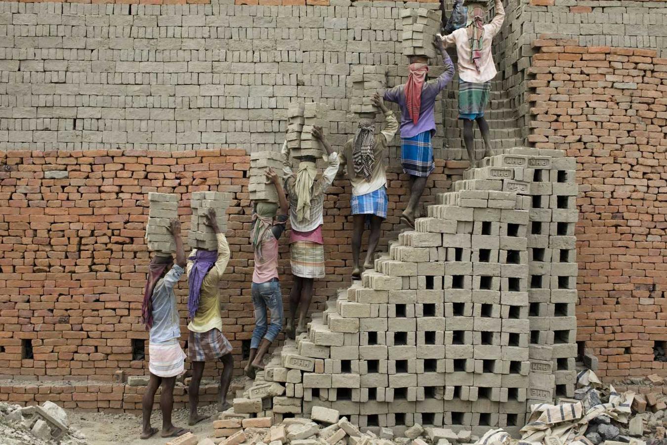 Trabajadores indios llevan ladrillos de arcilla a un horno de ladrillos en Farakka, en el estado indio de Bengala Occidental