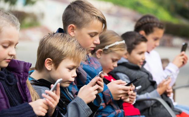 Un grupo de niños concentrados en sus teléfonos móviles. 