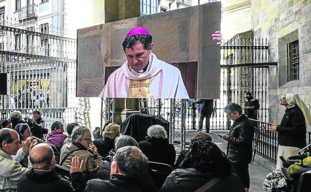 En pantalla. Un grupo de personas sigue la retransmisión de la ceremonia a través de la pantalla gigante instalada en el pórtico de Santiago. 