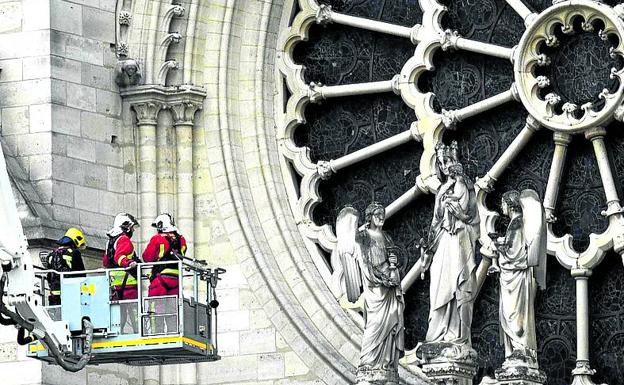 Tres bomberos junto a uno de los rosetones del templo. 