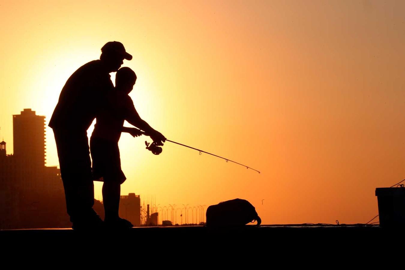 Siluetas de pescadores que permanecen en el muro del Malecón habanero al atardecer, en La Habana, Cuba. 