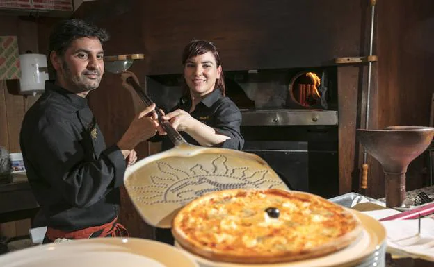 Patricia Galdos y Tareq Mahmood sostienen la pala empleada para meter las pizzas en el horno.