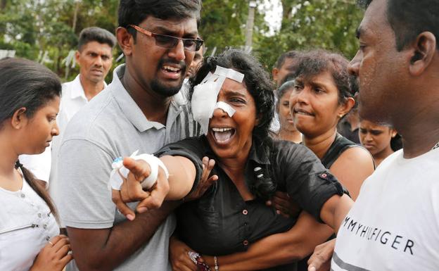 Kumari Fernando, que perdió a su marido y a dos hijos en el atentado en la iglesia de San Sebastián, señala entre gritos los féretros durante el funeral. :: Thomas Peter / reuters