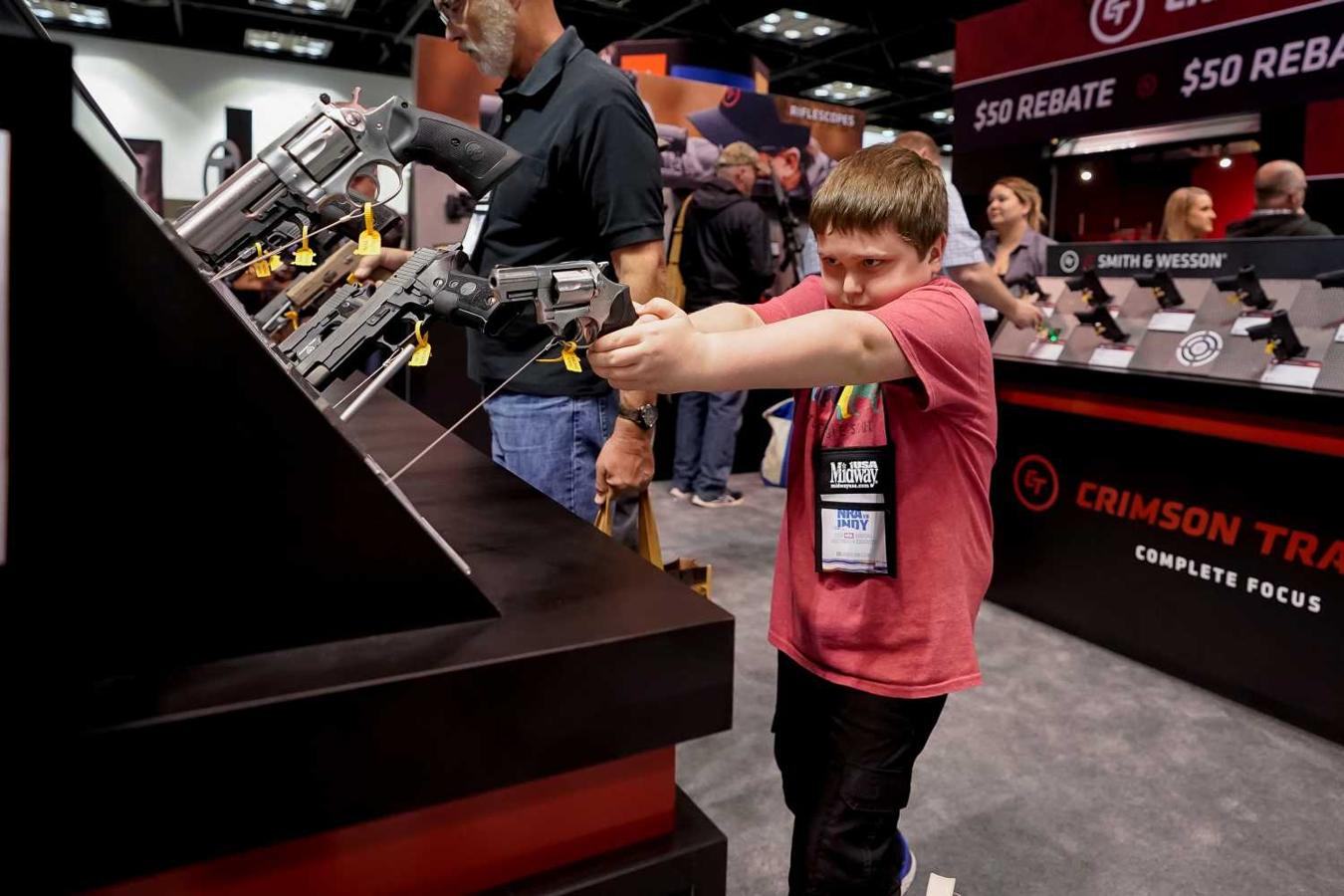 Un niño empuñando un arma en uno de los stands de la reunión anual de la Asociación nacional del Rifle, en Indianápolis, Estados Unidos.