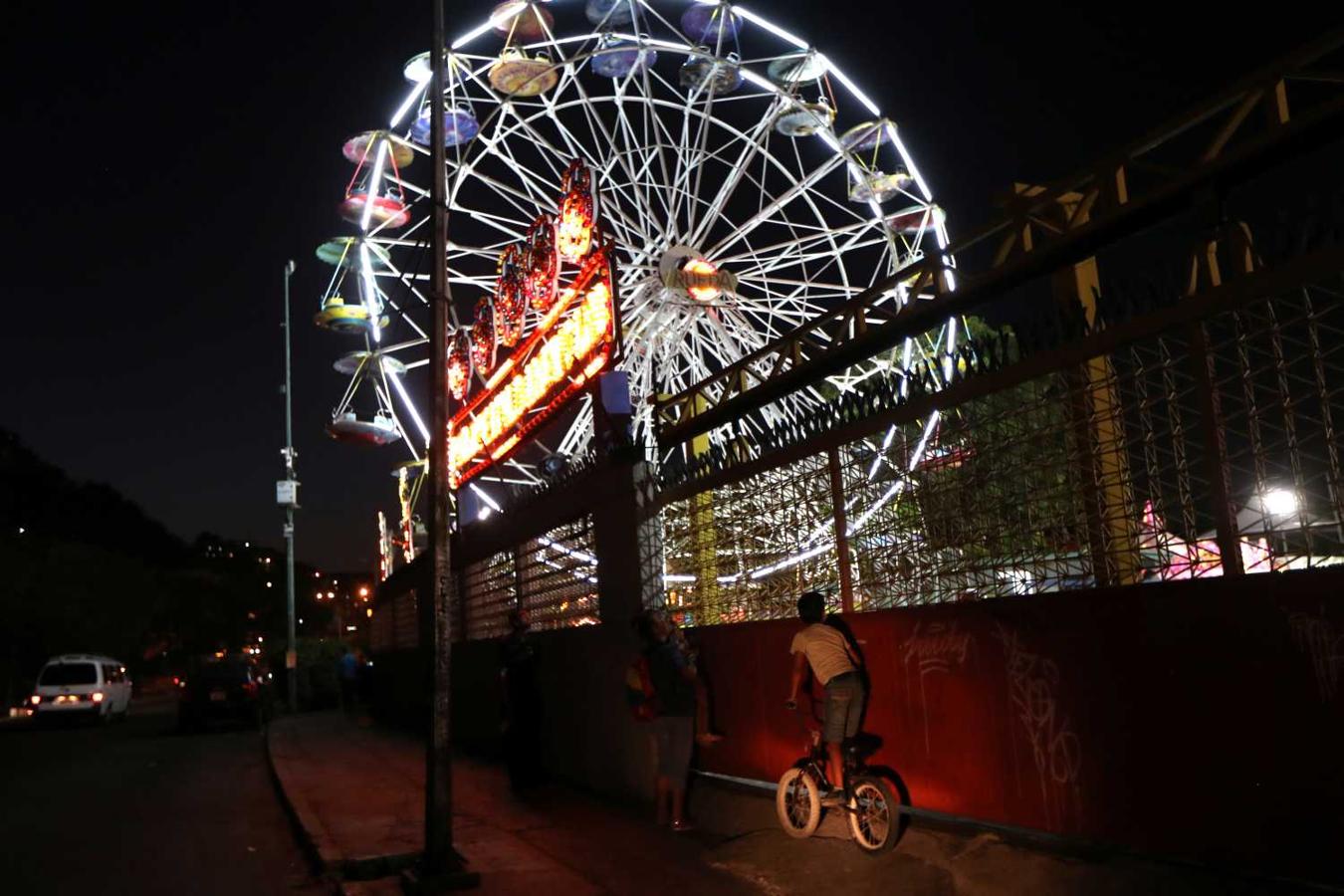 Un niño se sube a una bicicleta para la noria iluminada de un parque de atracciones en Caracas, Venezuela.