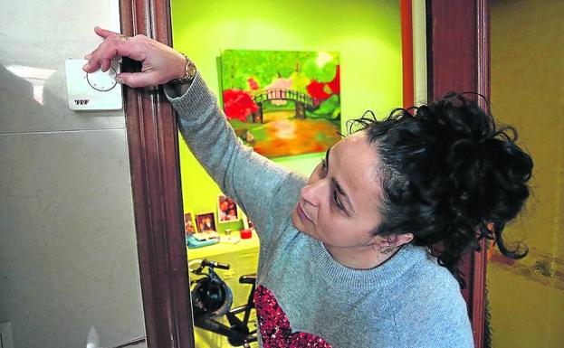 Una mujer ajusta el termostato en su vivienda.