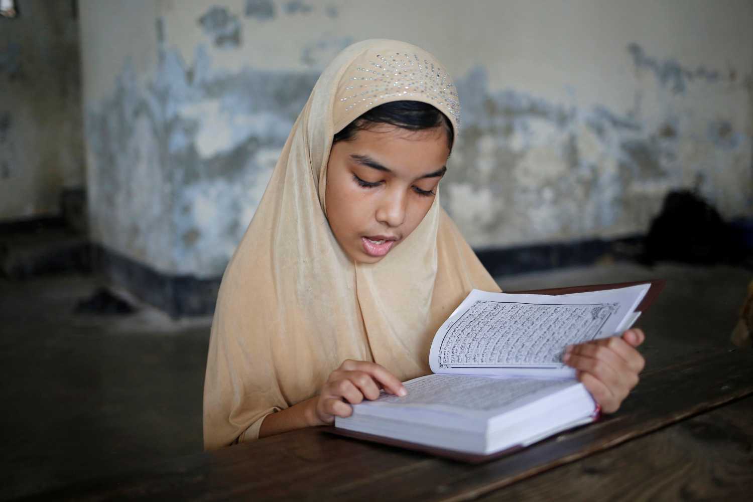 Una niña musulmana lee el Corán en la Madraza durante el Ramadán en Dhaka, Bangladesh