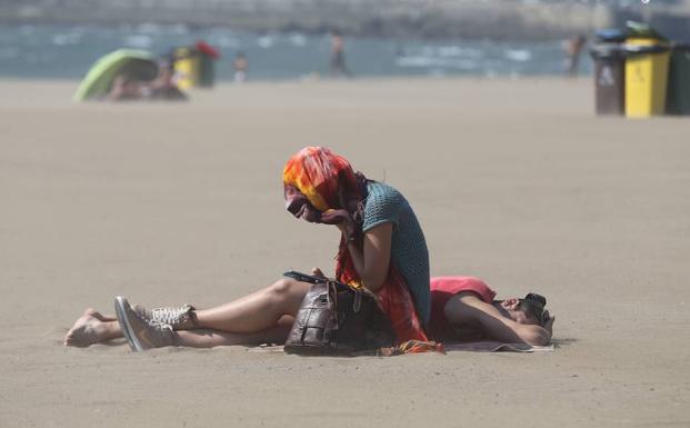 Una persona se protege de la arena en Ereaga, a consecuencia de una galernilla. 