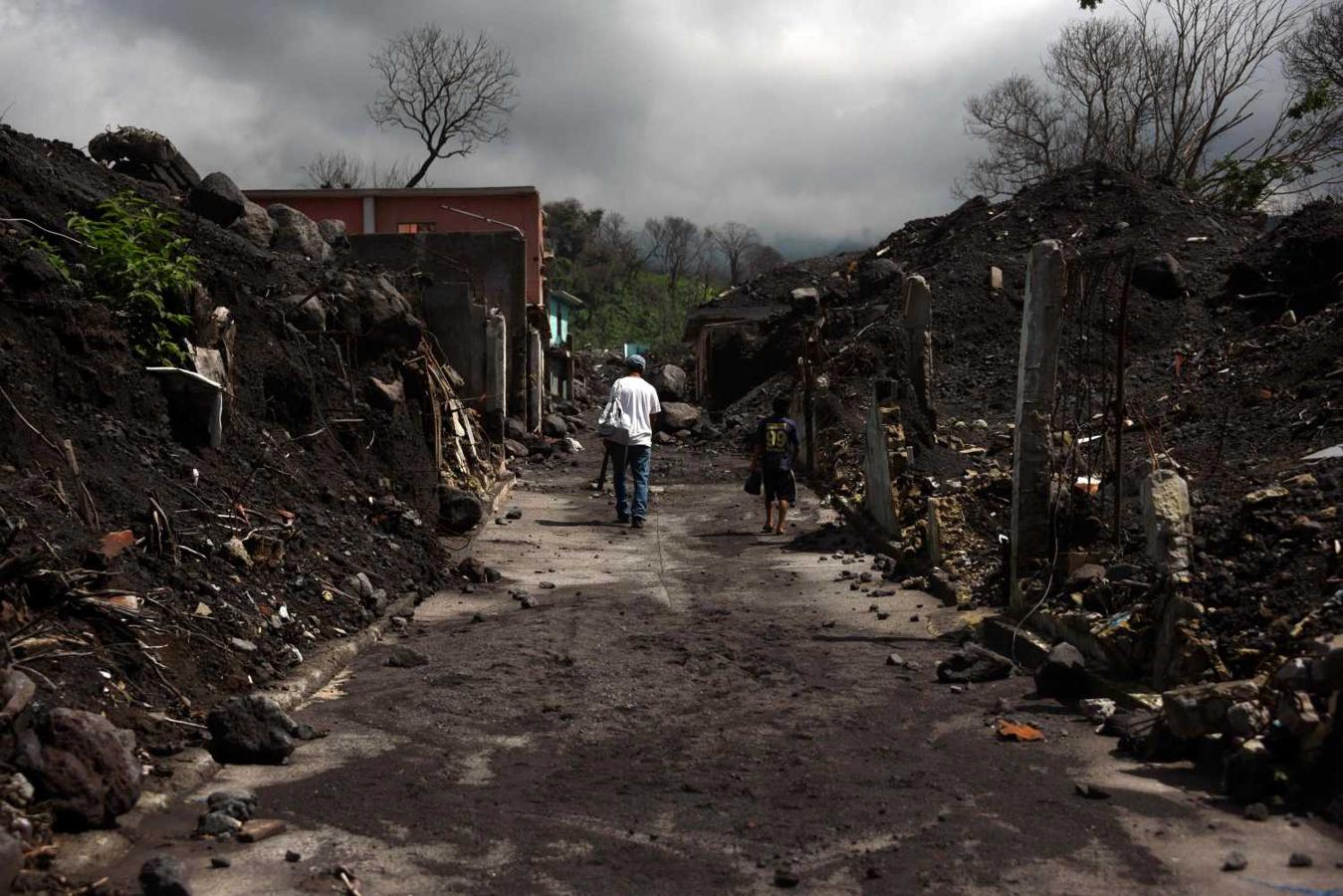 Un hombre y un niño caminan a la entrada del pueblo de San Miguel Los Lotes, destruido hace un año por la erupción del volcán de Fuego, en Guatemala