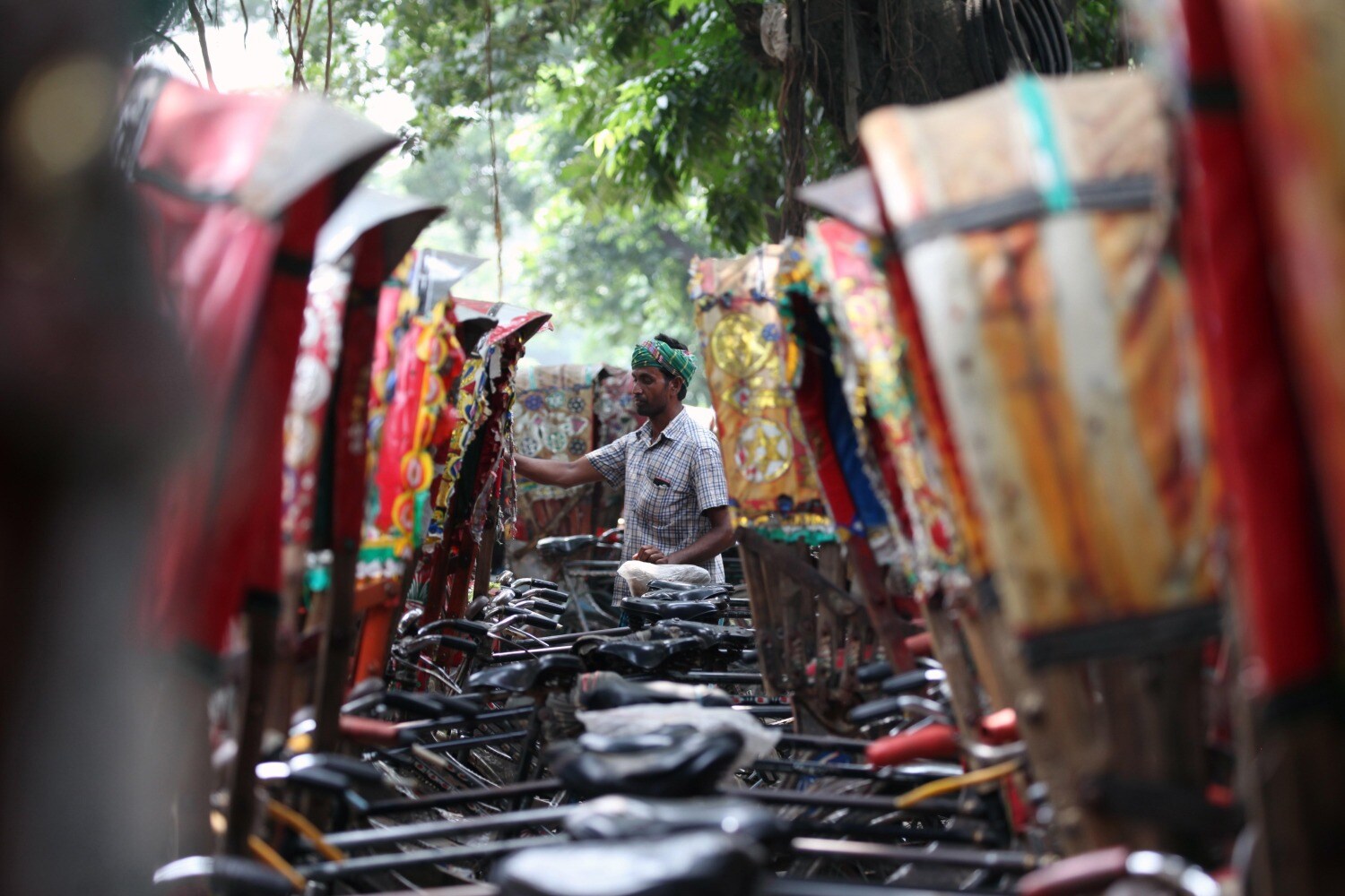 Un "bicitaxista" bangladés frente a un estacionamiento de "bicitaxis", en Daca, Bangladesh. 