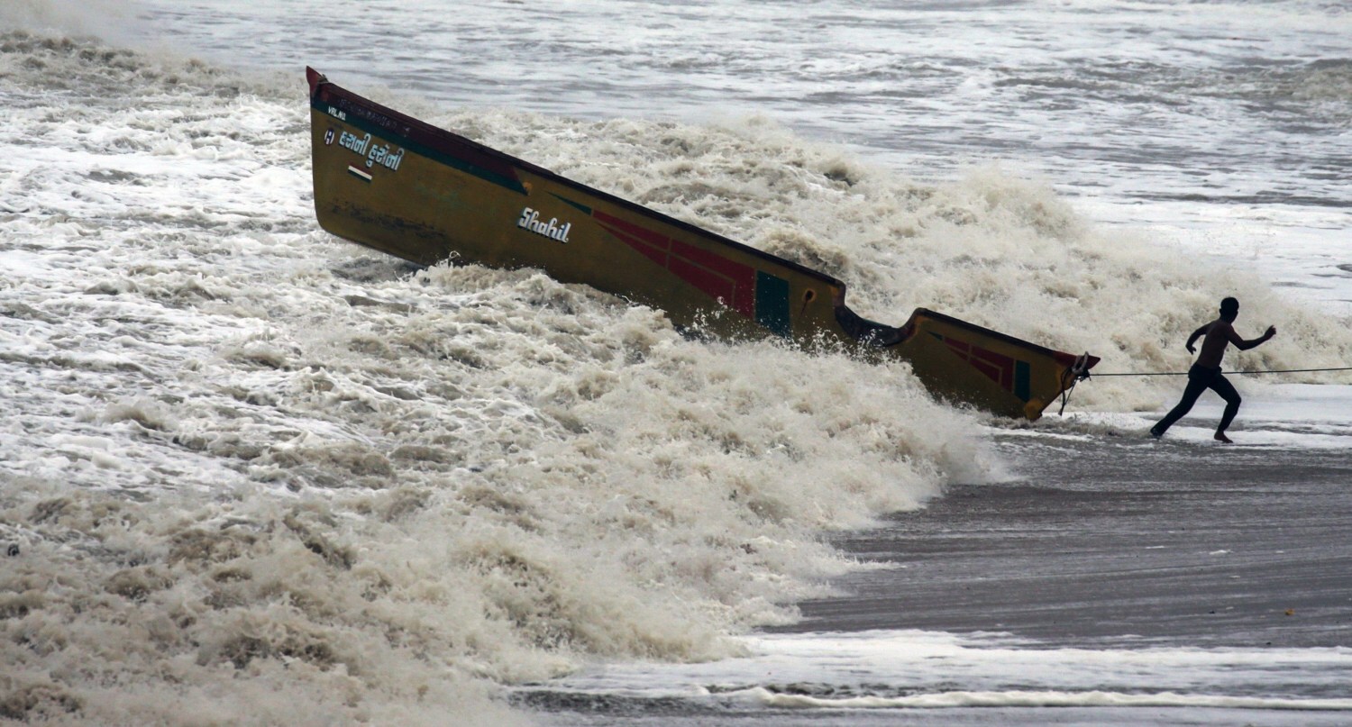 Pescadores sacan un bote del mar arábigo ante la pronta llegada del ciclón Vayu a Veraval (India). 