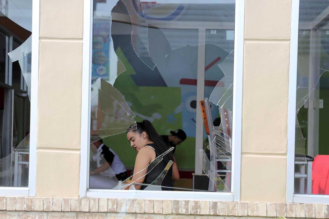 Empleados de una empresa recogen los cristales rotos tras las protestas en Tegucigalpa (Honduras)