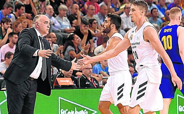Pablo Laso choca las manos con Campazzo y Caroll. 