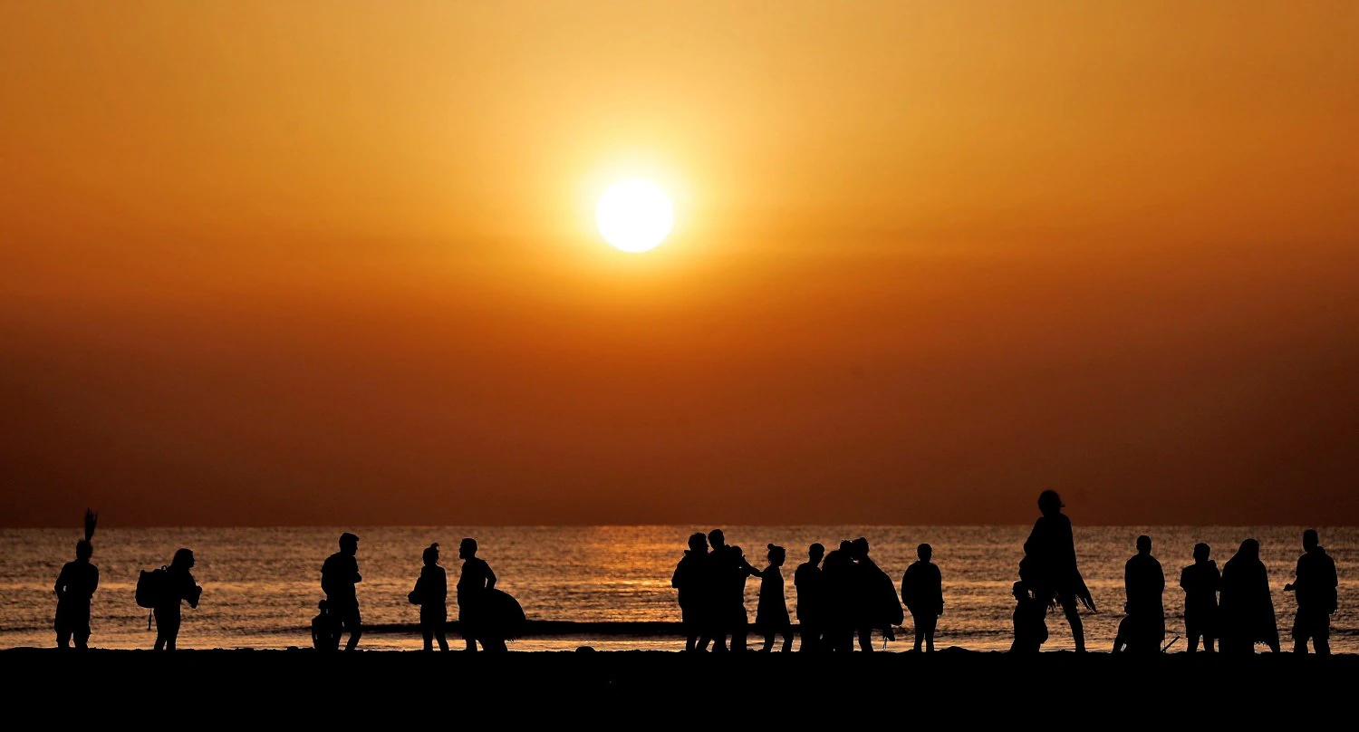 Numerosos jóvenes recogen sus cosas tras ver amanecer en la playa de la Malvarrosa de Valencia tras celebrar la noche de San Juan.