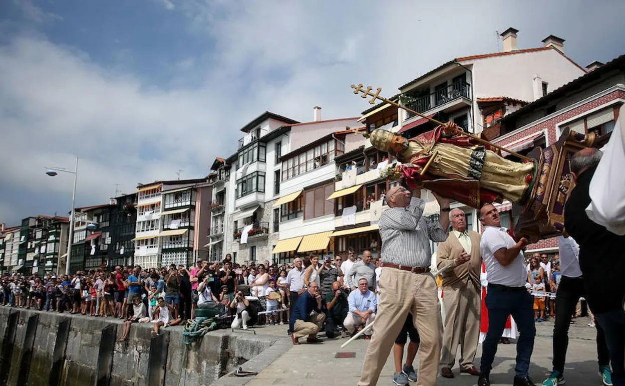 Miembros de la cofradía de Lekeitio inclinan la figura de San Pedro ante la atenta mirada del público. 