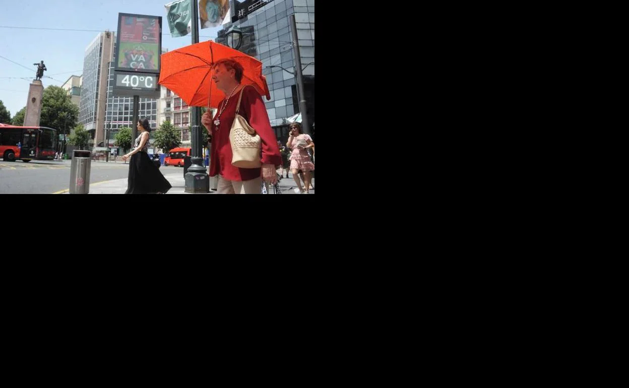 Una mujer se protege del sol en el centro de Bilbao con un paraguas.
