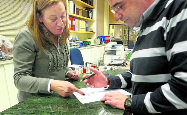 Un padre cumplimenta la inscripción de su hijo en la administración de un centro escolar.