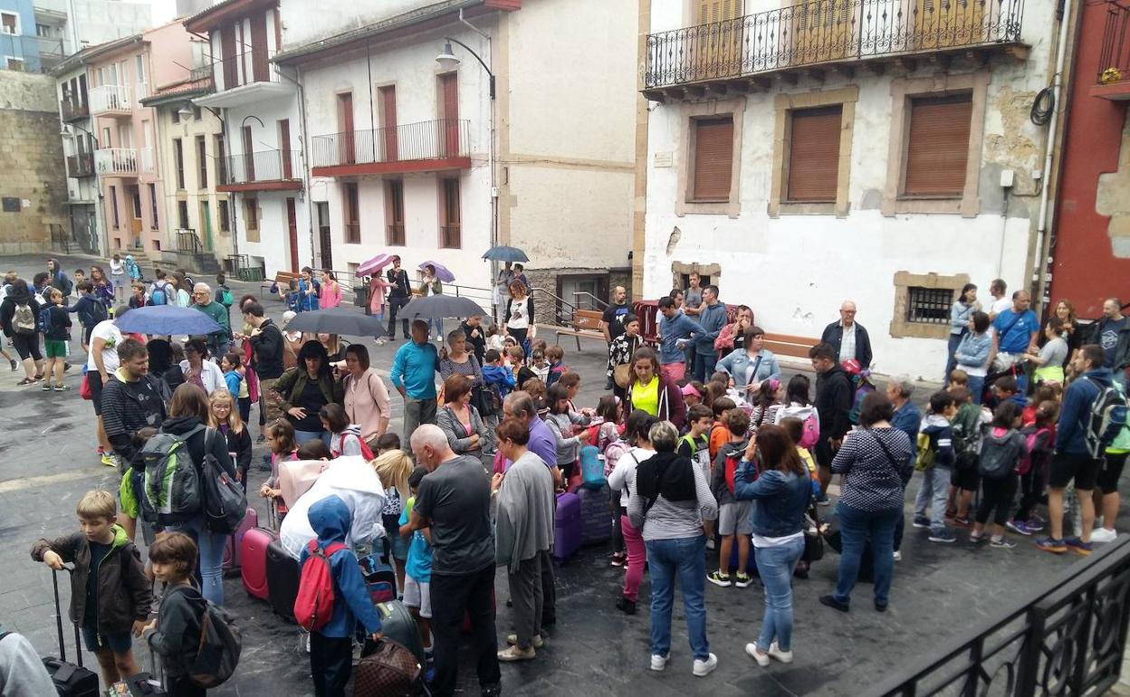 Preparativos con maletas. Madres y padres se despiden de niñas y niños antes de la salida.