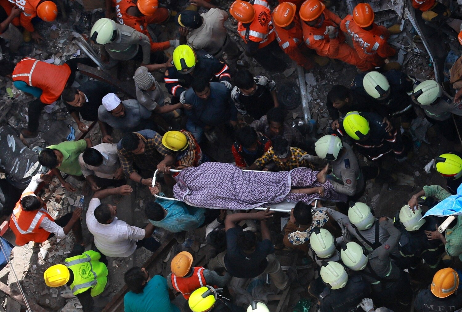 Miembros de los servicios de rescate retiran el cadáver de una víctima tras el derrumbe de un edificio en Bombay (India).