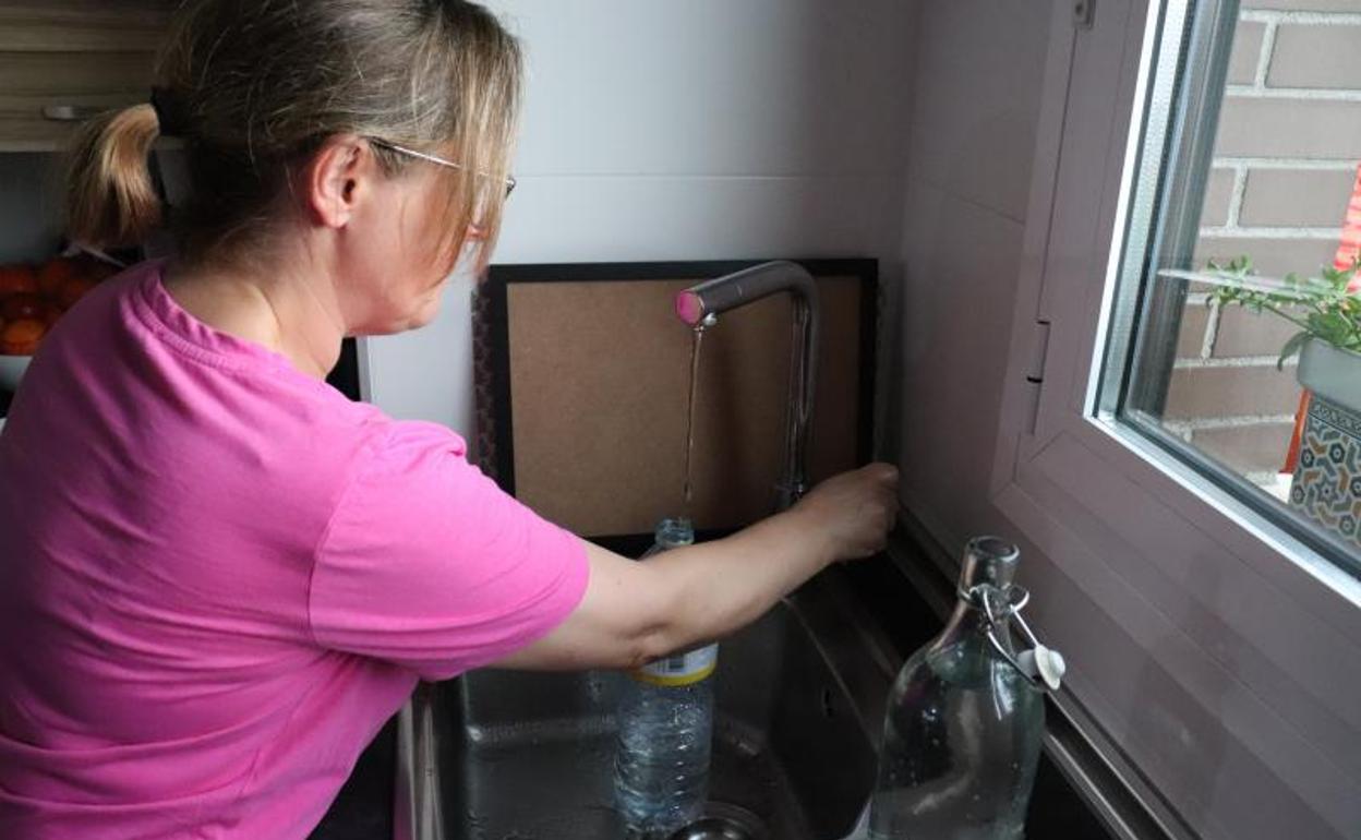 Una vecina de Uribe llena una botella de agua tras recuperar el suministro. 